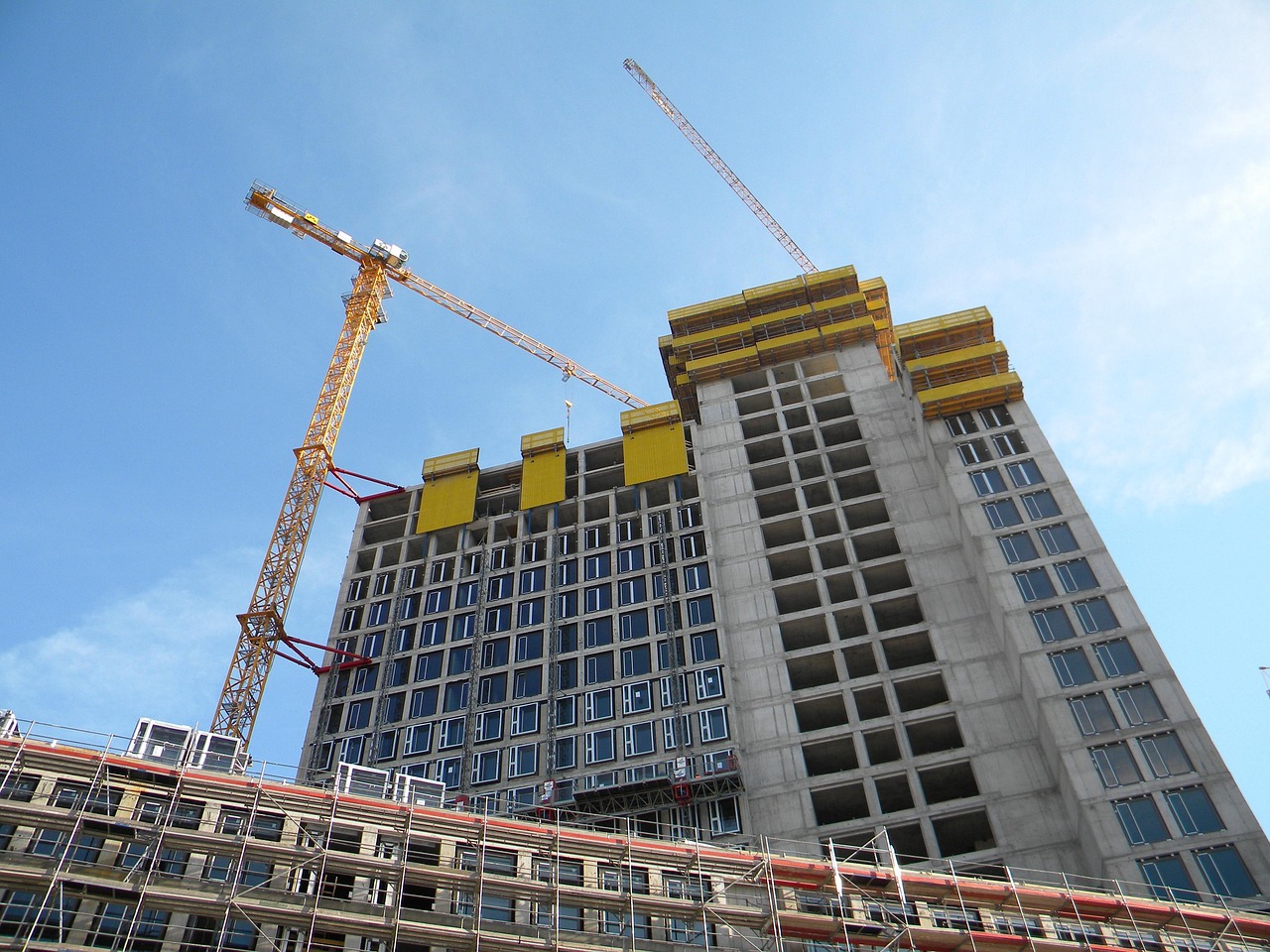 בניין מגורים גבוה בבנייה, עם עגורנים ופיגומים: חלק מהקומות כבר עם חלונות, והעליונות עדיין בשלד